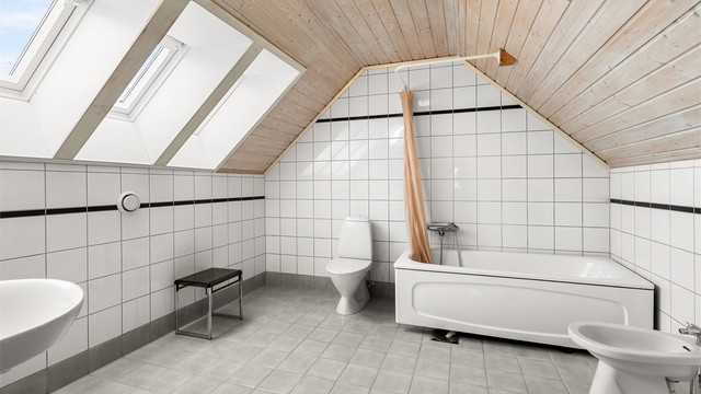 Romslig bad i loftsetasjen på 9,5 kvm med flislagte overflater, gulvvarme og takvinduer som slipper inn godt med naturlig lys.