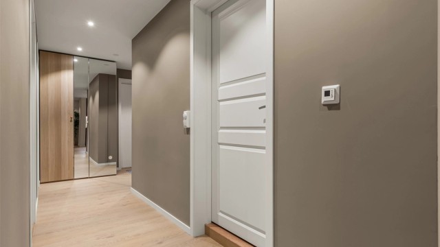 Romslig entré med en-stavs laminatgulv og downlights i himling.