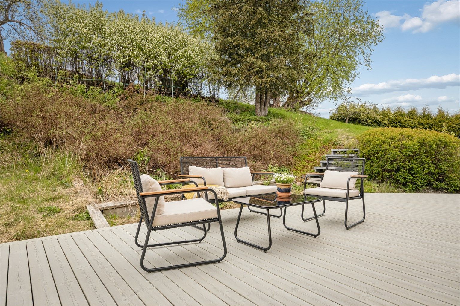 Fin uteplass på terrasseplatting med plass til flere sitteområder