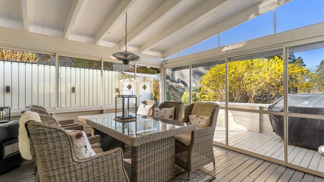 Den innglassede terrassen fungerer som en forlengelse av stuen og har skyvedører ut til den åpne terrassen.