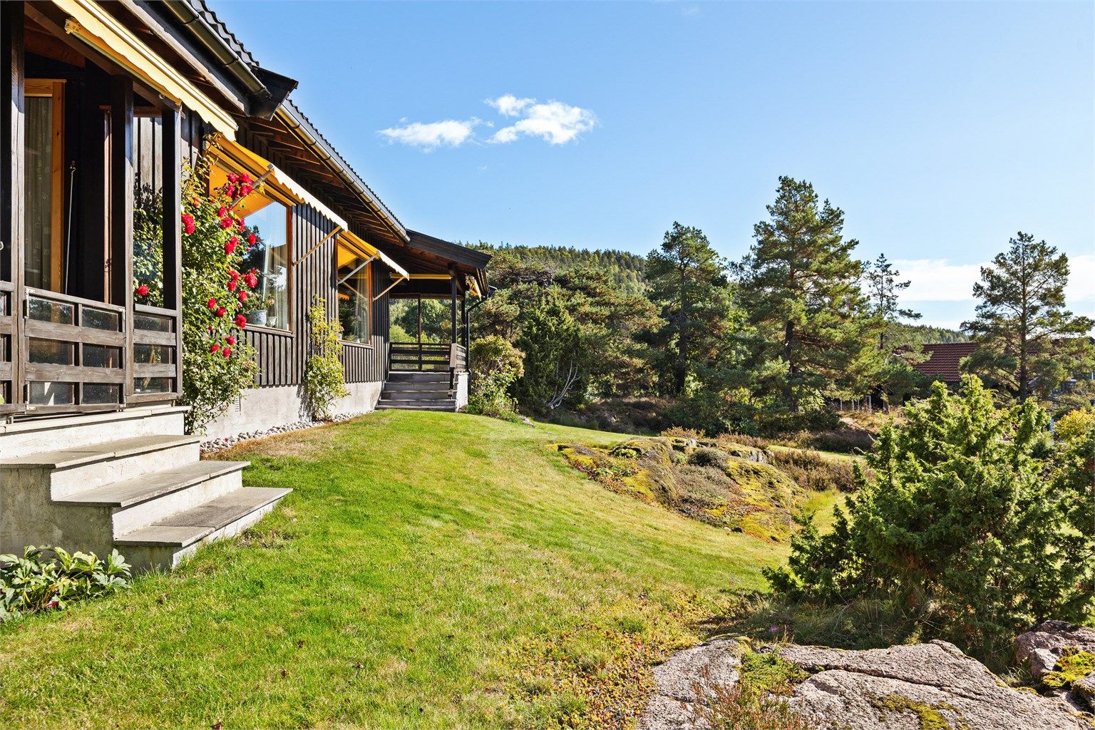Tomten har gressplen og naturlige fjellknauser som glir inn i terrenget.