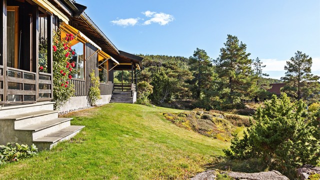 Tomten har gressplen og naturlige fjellknauser som glir inn i terrenget.
