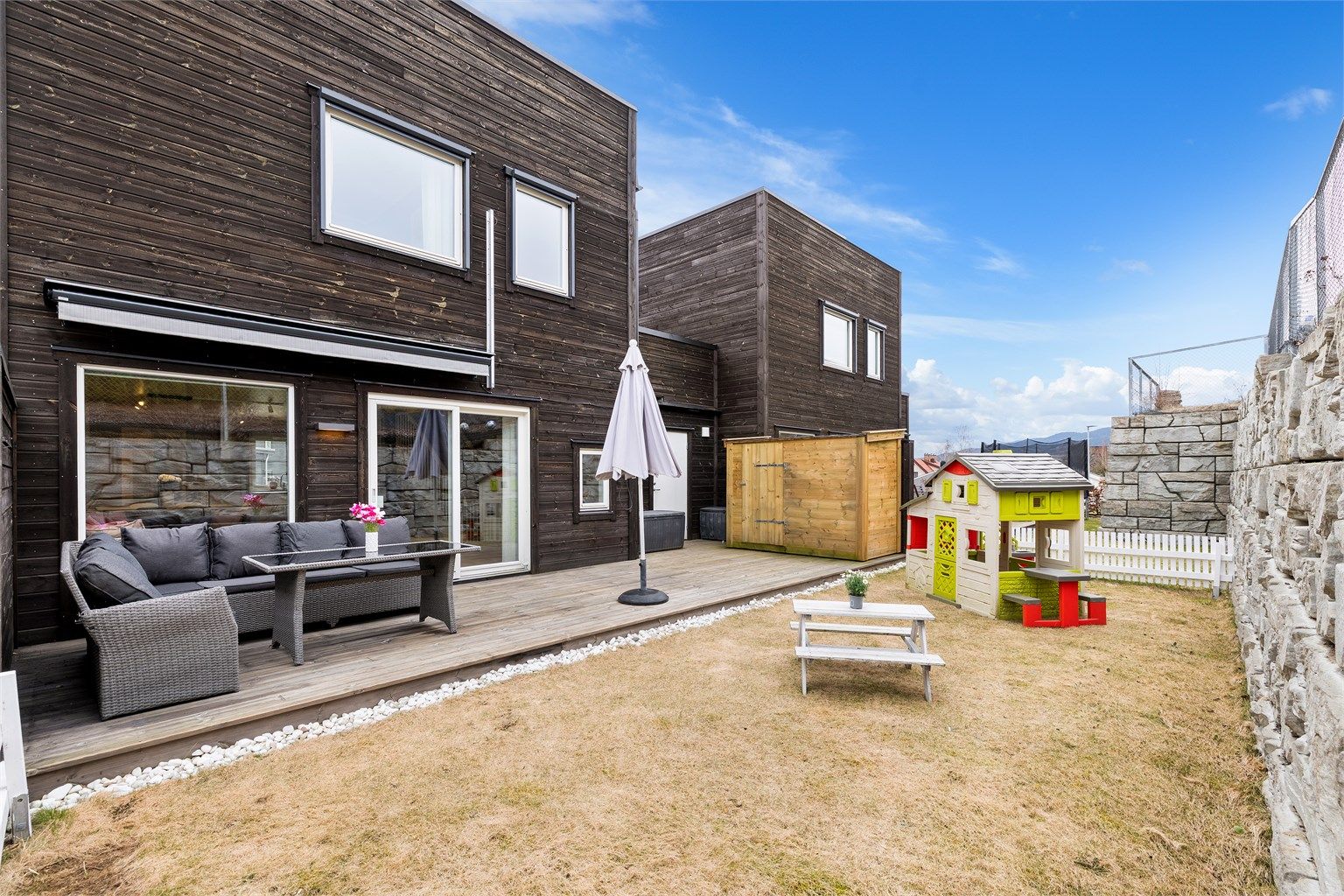 Fra stuesiden er det utgang til en hyggelig markterrasse med fin terrassemarkise og praktisk lagringsbod for utemøbler mm. Fint plenareale som innbyr til lek for viltre småtasser