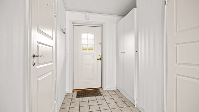 Entré med flislagt gulv og plass til oppbevaring i garderobeskap.