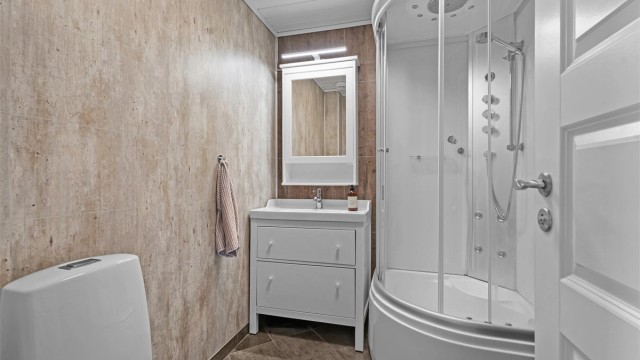 Badet i første etasje ble oppgradert i 2015/16. Flislagt gulv med gulvvarme, baderomsplater på vegger, dusjkabinett, gulvstående servantinnredning og toalett.