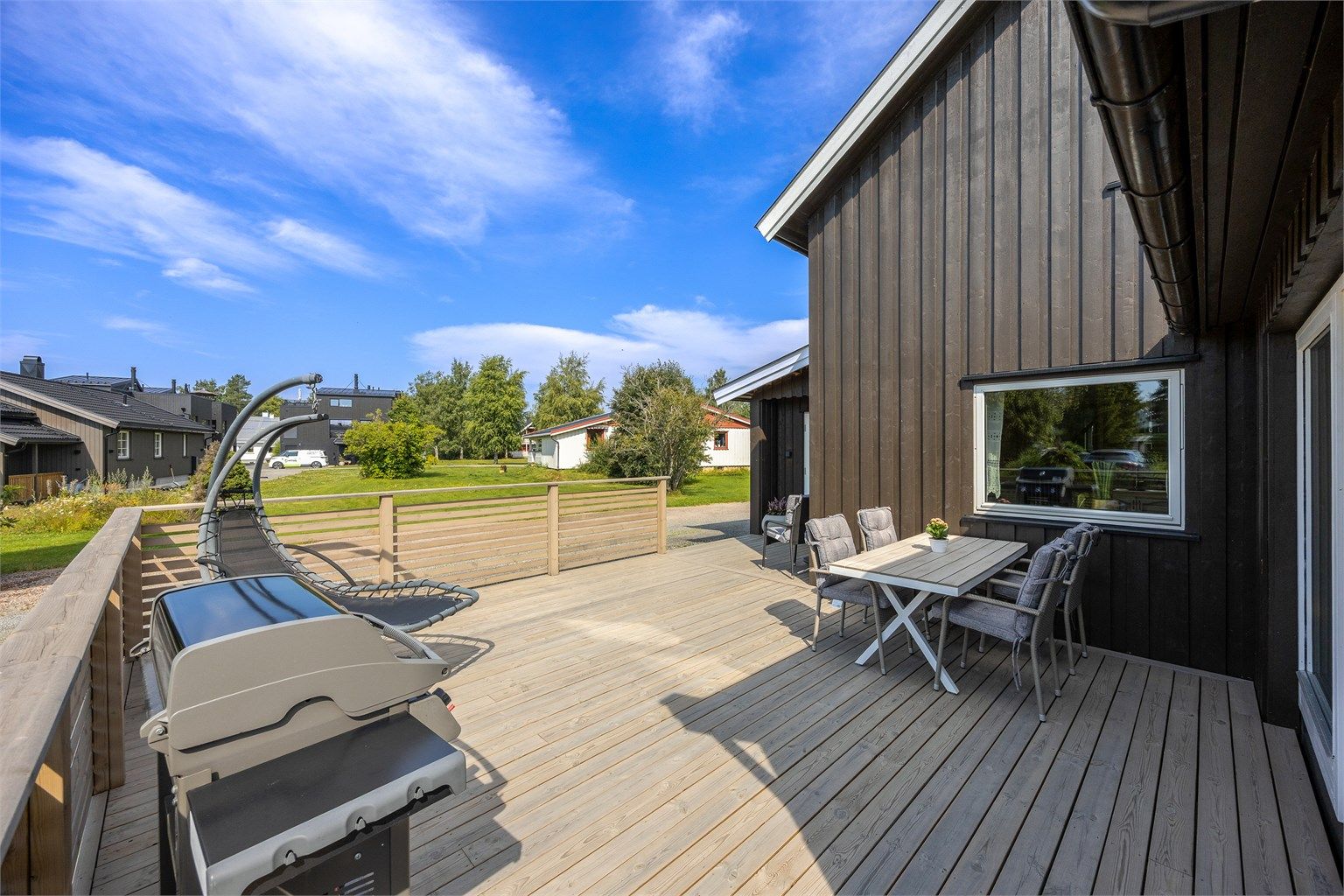 Terrassen er bygget med terrassebord og har rekkverk av tre.