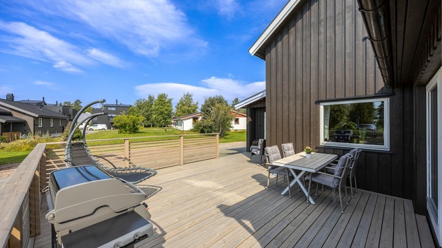 Terrassen er bygget med terrassebord og har rekkverk av tre.