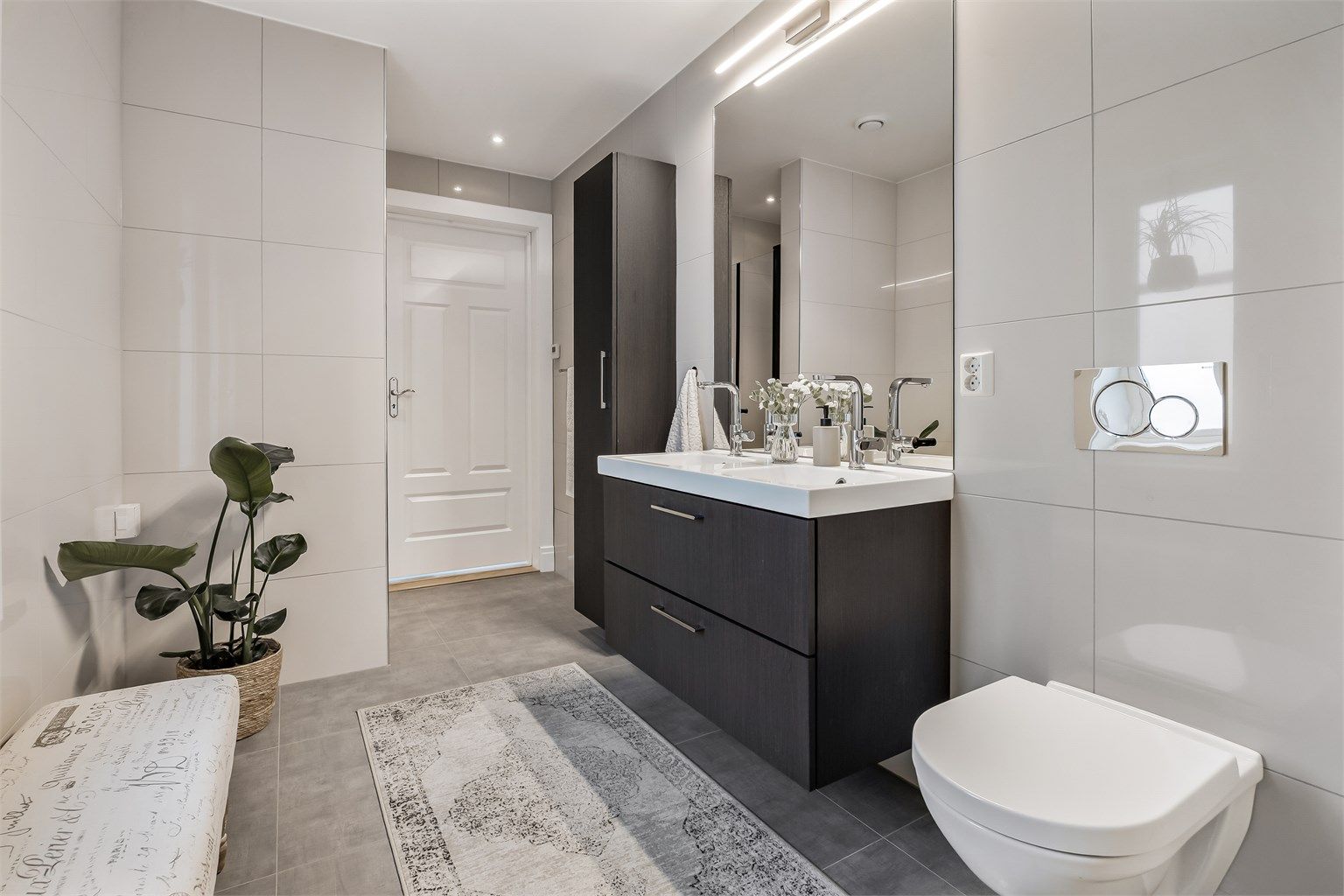 Badet i første etasje er flislagt og har en mørk innredning med dobbel servant.