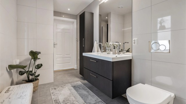 Badet i første etasje er flislagt og har en mørk innredning med dobbel servant.