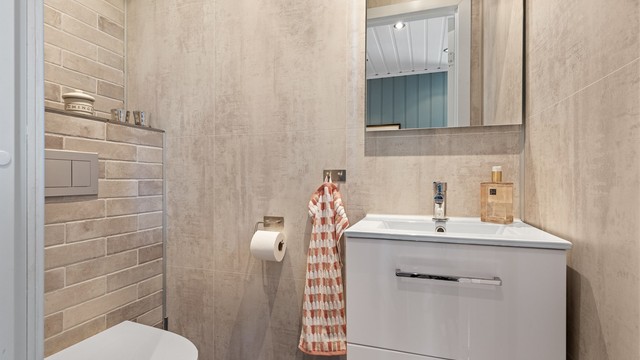 Pent oppusset wc rom med varmekabler i gulvet for lun varme i rommet. Moderne baderomsmøbel i hvit høyglans utførelse.