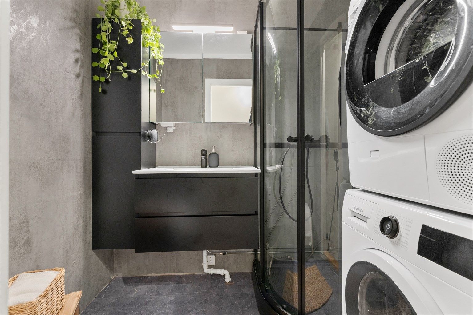 Badet er moderne innredet med dusjkabinett, servantinnredning og opplegg for vaskemaskin.