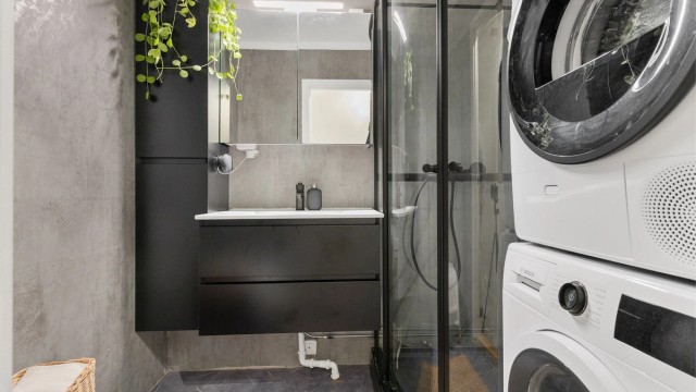 Badet er moderne innredet med dusjkabinett, servantinnredning og opplegg for vaskemaskin.