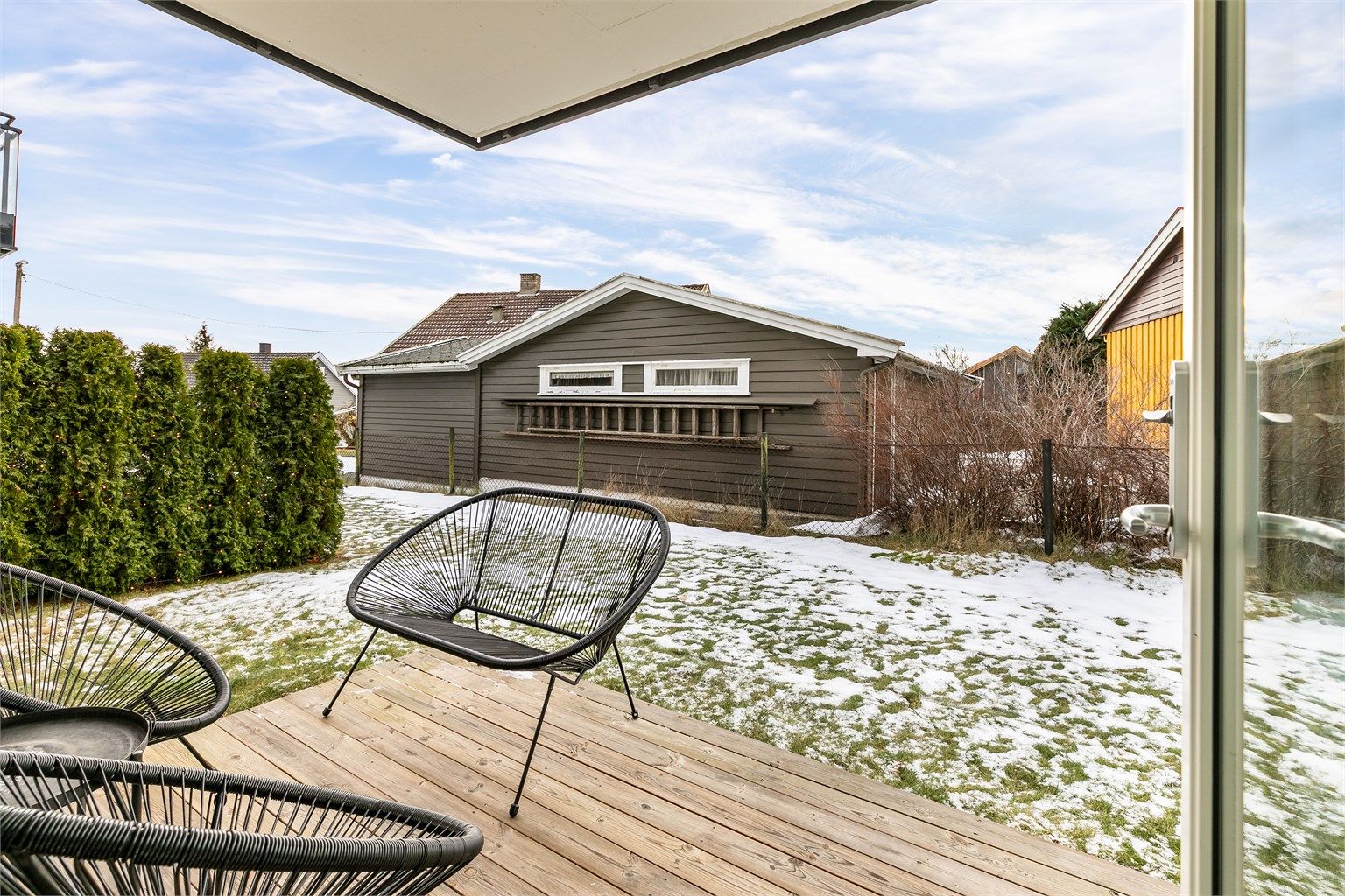 Fra plattingen kan du gå rett ut på plenen i sameiets hage. Tettvoksende thujahekker begrenser innsyn fra sidenaboer.