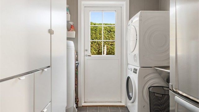Praktisk vaskerom med flislagt gulv, opplegg for vaskemaskin, varmtvannsbereder fra 2019 og egen utgangsdør.