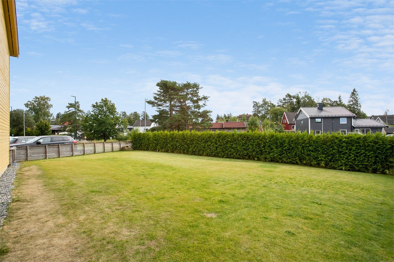 Egen hage med plen, avgrenset med hekk og gjerde.