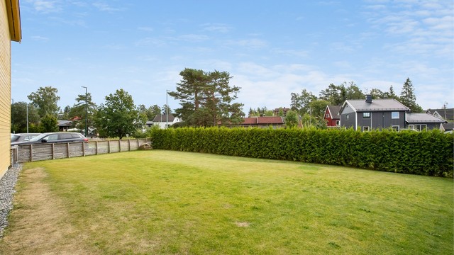 Egen hage med plen, avgrenset med hekk og gjerde.
