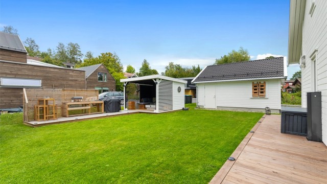 Hage med plen, platting og pergola.