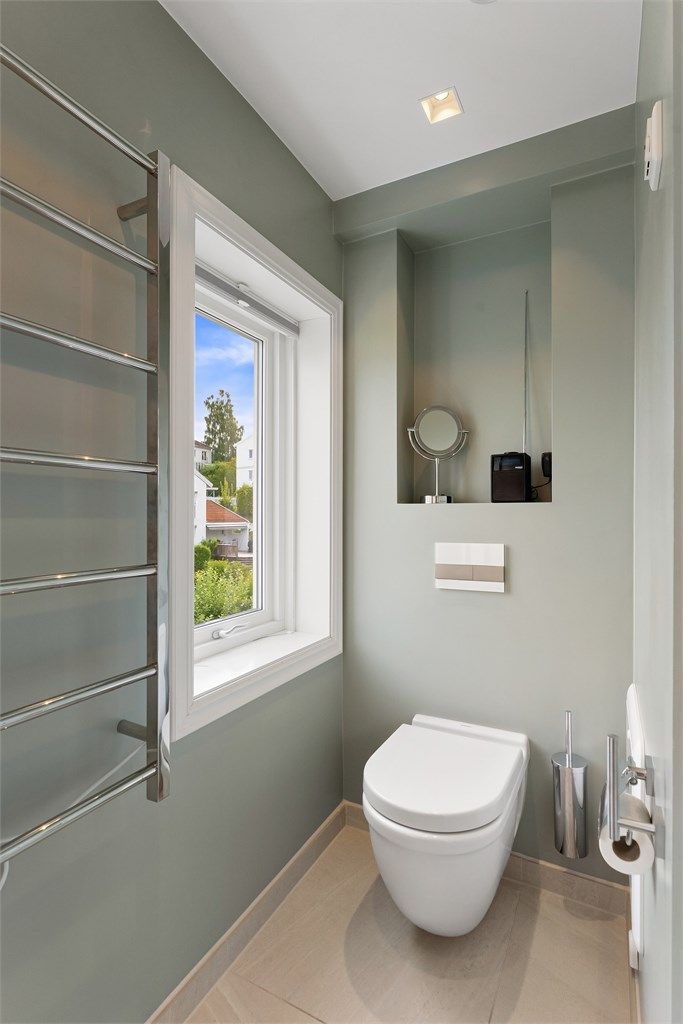 Badet har vegghengt toalett og nedsenket himling med downlights.