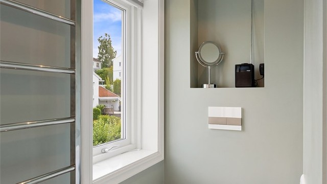Badet har vegghengt toalett og nedsenket himling med downlights.