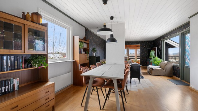 Den åpne planløsningen mellom stue, spisestue og kjøkken skaper en luftig og sosial atmosfære.