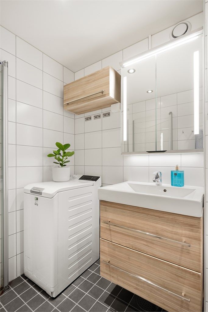 Innredningen inkluderer servantskap, speilskap med belysning og opplegg for vaskemaskin.