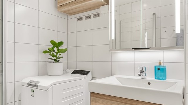 Innredningen inkluderer servantskap, speilskap med belysning og opplegg for vaskemaskin.