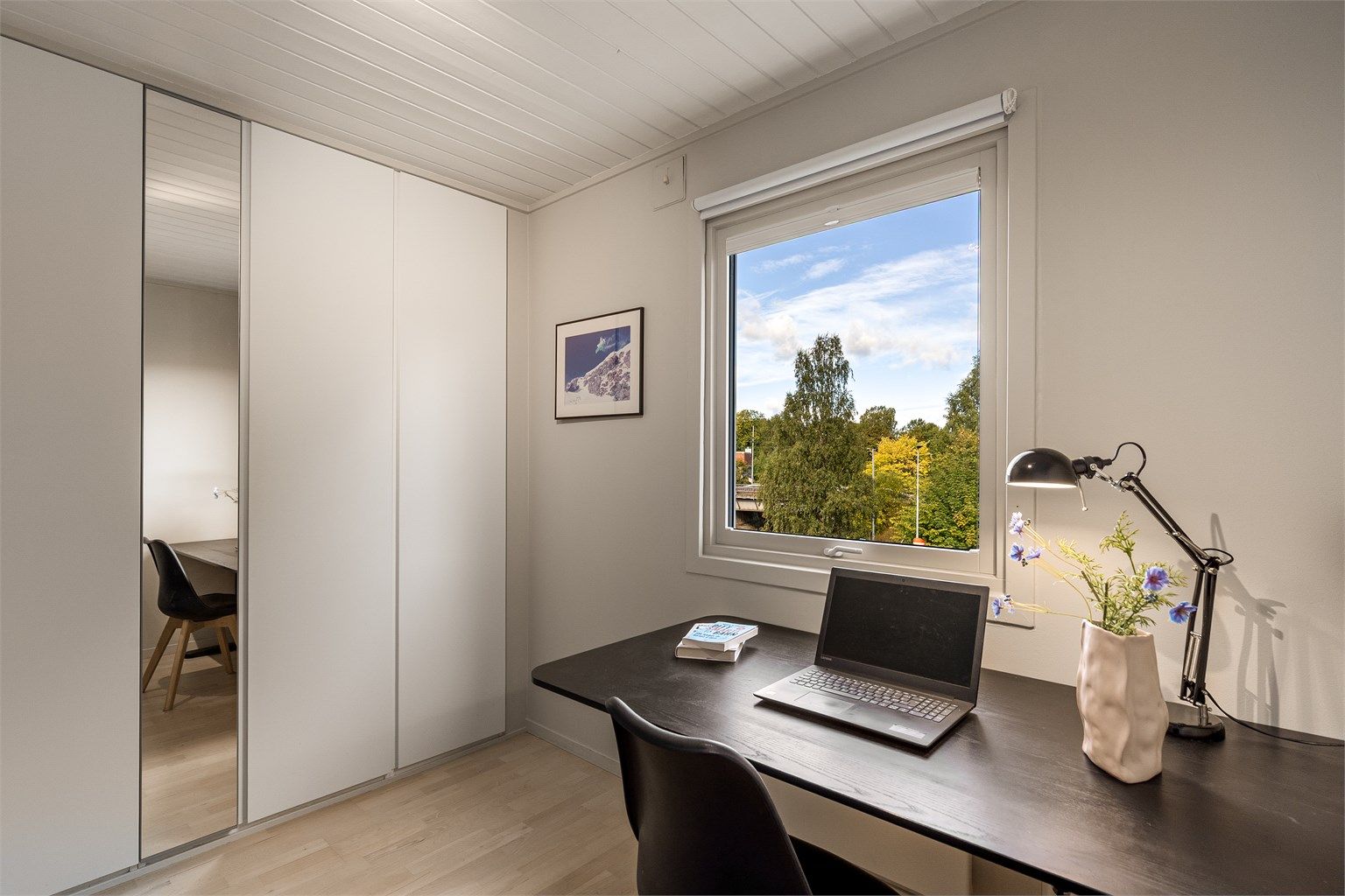 Garderobeskap med speildør og utsikt mot nærområdet fra skriveplassen.