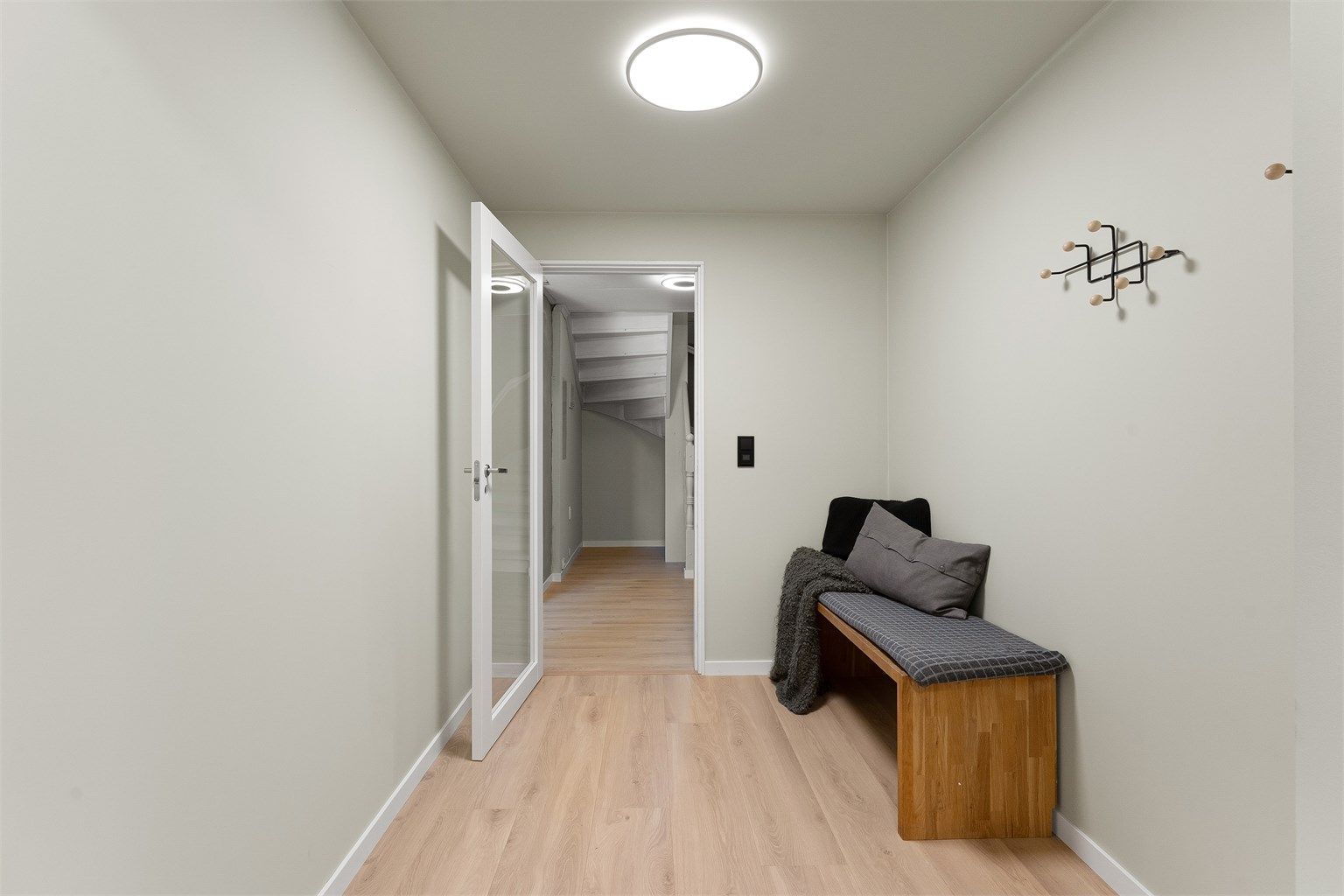 Fra entréen er det videre adkomst til gangen som fordeler til etasjens øvrige rom og trapp opp til første etasje.