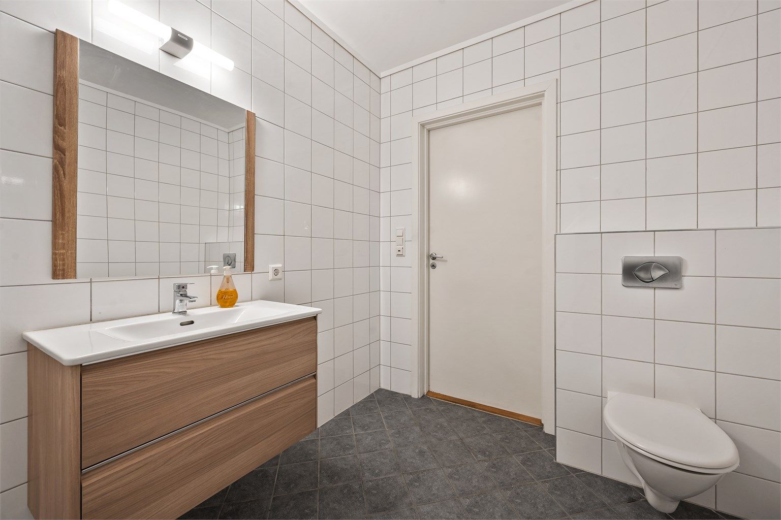 Flislagt bad med servantskap, dusjhjørne og toalett