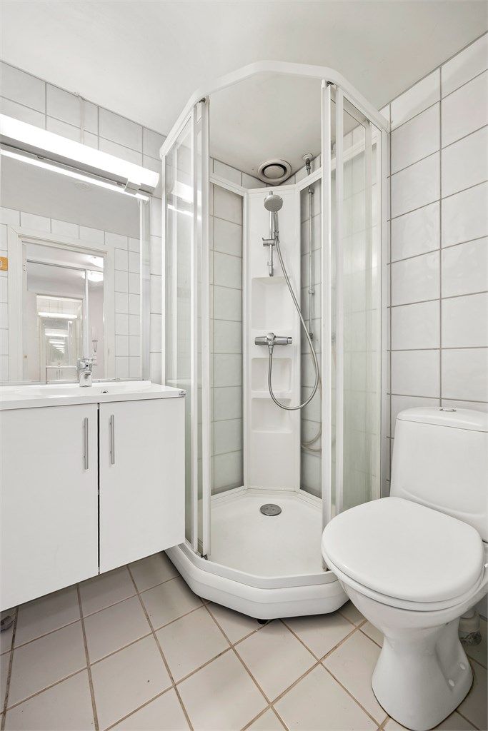 Badet har gulvstående toalett og dusjkabinett