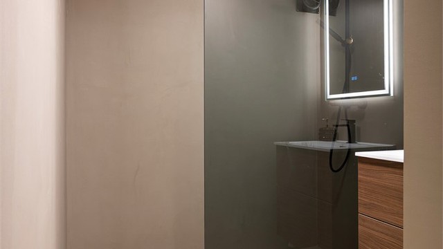 Badet er stilfullt pusset opp i 2026 med microsement på gulv og vegger, nytt dusjhjørne og nye møbler. I gulvet er det varmekabler av eldre årgang.