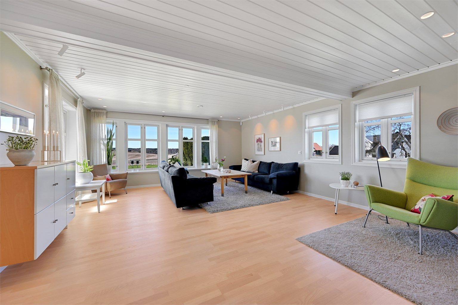 Stuen er romslig med plass til flere soner, og har parkett på gulv og malte panel i tak.