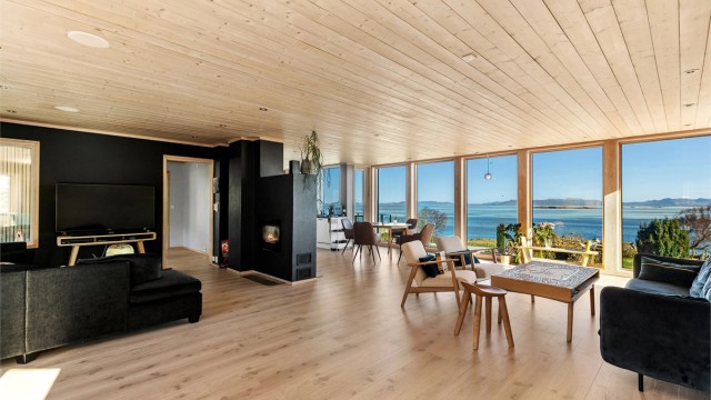 Stuen og kjøkkenet utgjør et stort allrom med panelbord i himling og store vindusflater som rammer inn utsikten mot sjøen.