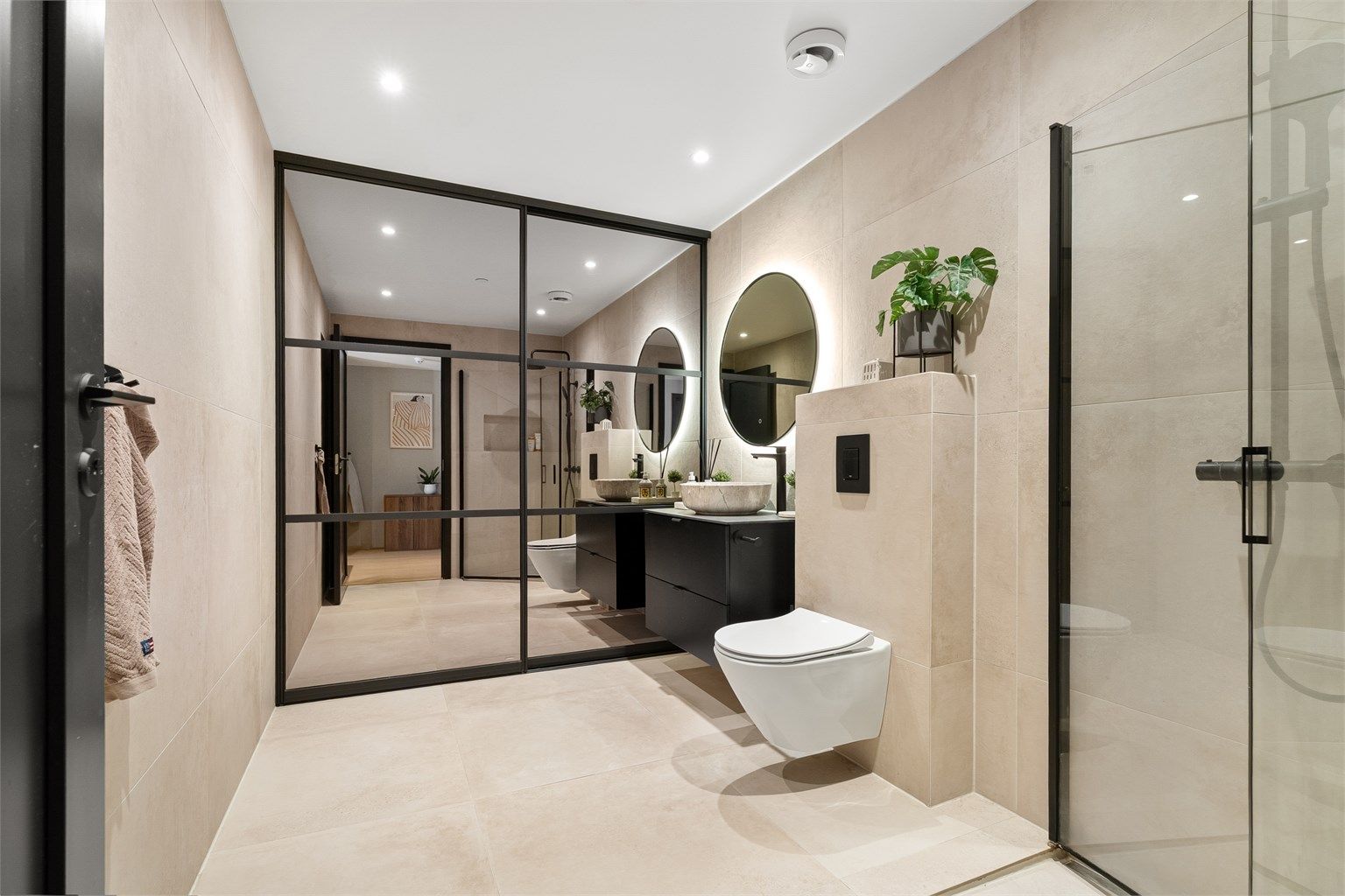 Innholdsrikt og flislagt bad med gulvvarme. Bak skyvedørsgarderobe skjuler det seg både opplegg til vaskemaskin/tørketrommel, ekstra oppbevaring og klesoppheng. 