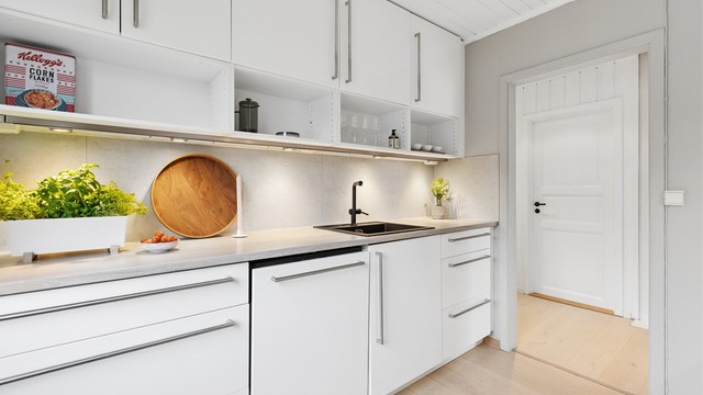 Kjøkkeninnredning med glatte fronter, laminat benkeplate og belysning under overskapene.