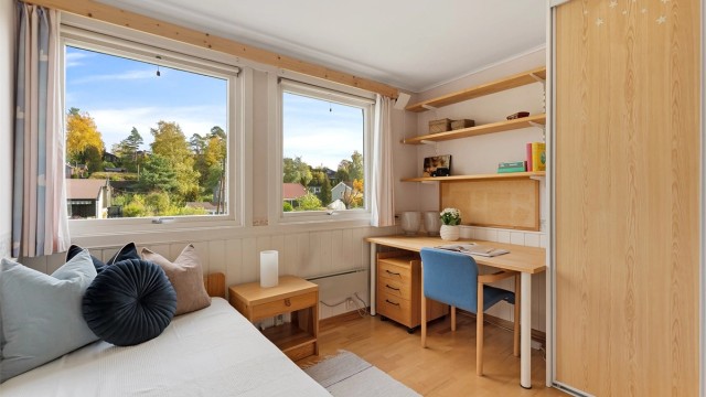 Rommet er utstyrt med garderobeskap og praktisk arbeidsplass under vinduet.