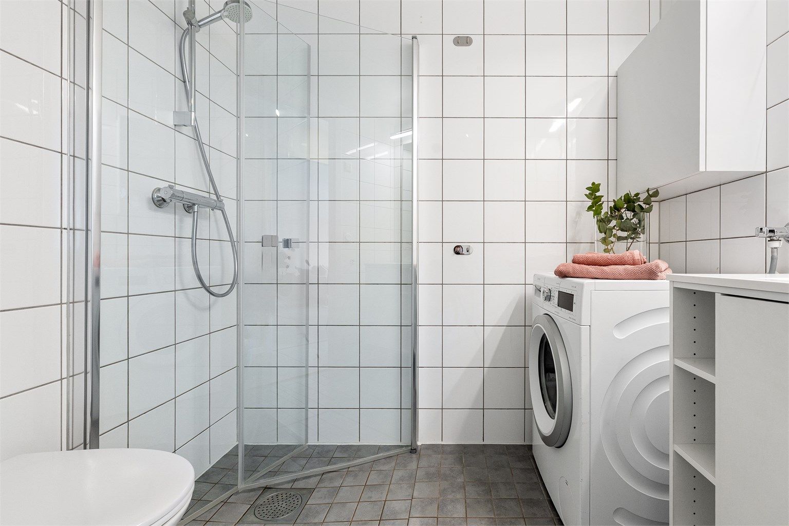 Rommet er utstyrt med dusjhjørne med dører, vegghengt toalett og servantmøbel.