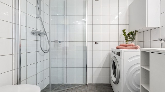 Rommet er utstyrt med dusjhjørne med dører, vegghengt toalett og servantmøbel.