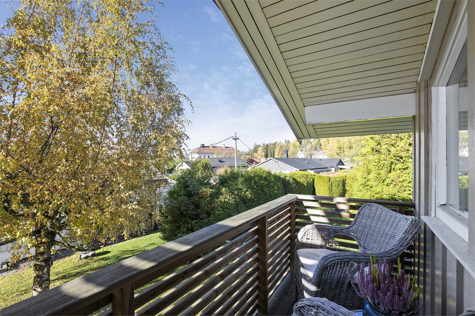 Skjermet balkong belagt med terrassebord og utsyn mot hagen.
