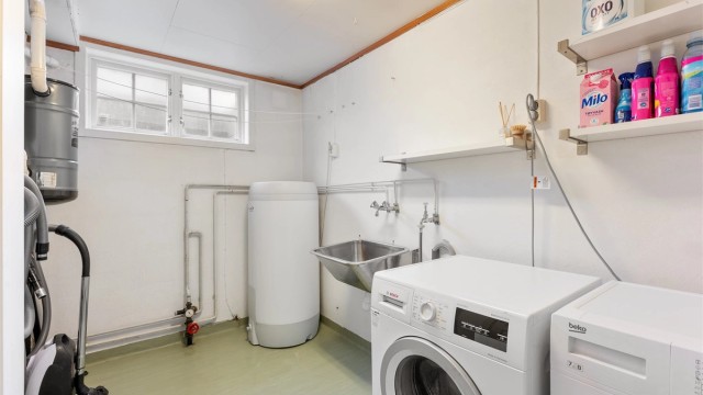 Praktisk vaskerom med varmekabler, opplegg for vaskemaskin og plassering av sentralstøvsuger.