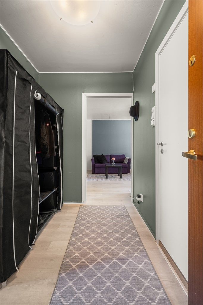 Entréen ønsker velkommen med laminatgulv og malte veggflater, og leder videre til leilighetens øvrige rom.