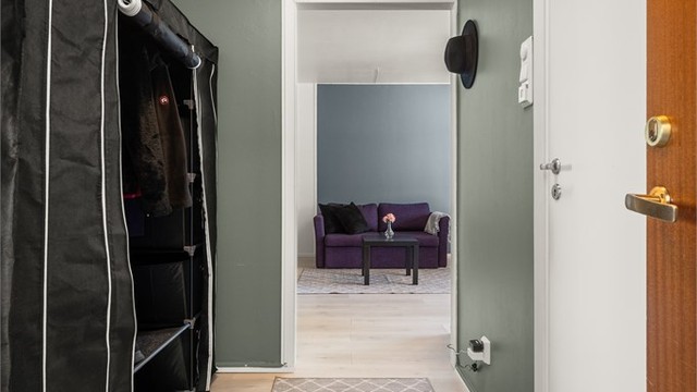 Entréen ønsker velkommen med laminatgulv og malte veggflater, og leder videre til leilighetens øvrige rom.