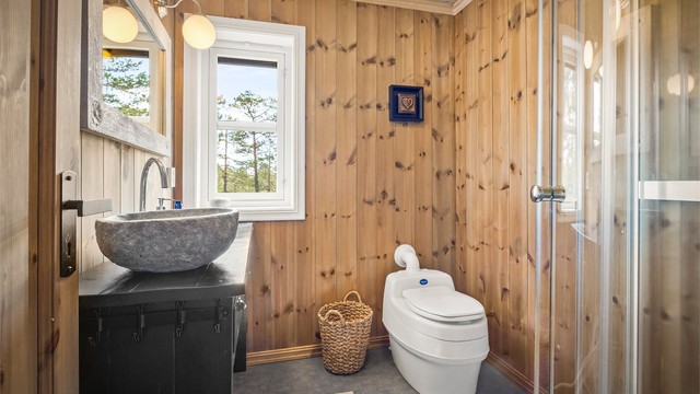 Videre er det dusjkabinett med skyvedører og gulvstående tørrtoalett.