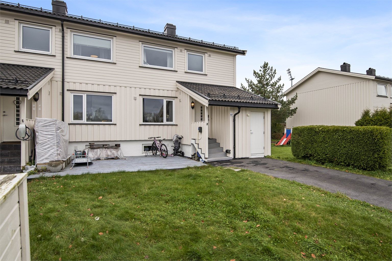 Asfaltert gårdsplass med elbillader montert på veggen