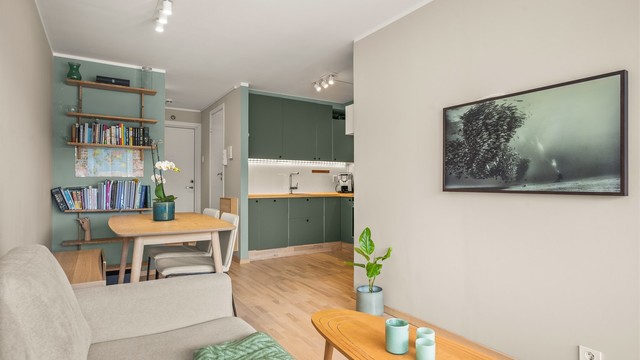 Et stilrent kjøkken i åpen løsning mot stuen skaper en sosial og naturlig atmosfære.