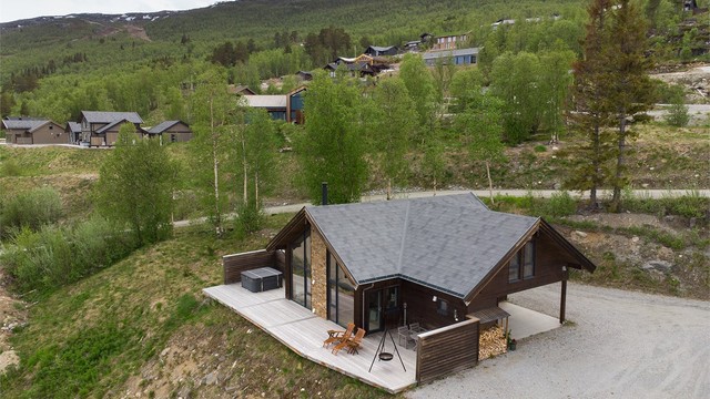 Hytta ligger fint til i skrånende terreng med store vindusflater mot sør.