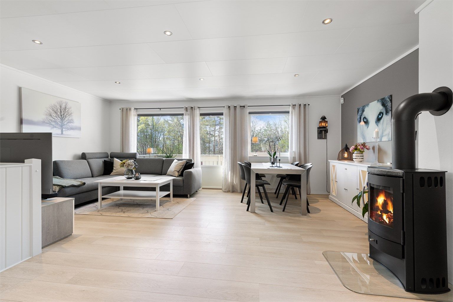 Andre etasje er boligens sosiale sone, med en åpen planløsning som forener stue og kjøkken. Peisovnen fra byggeåret gir en lun atmosfære.