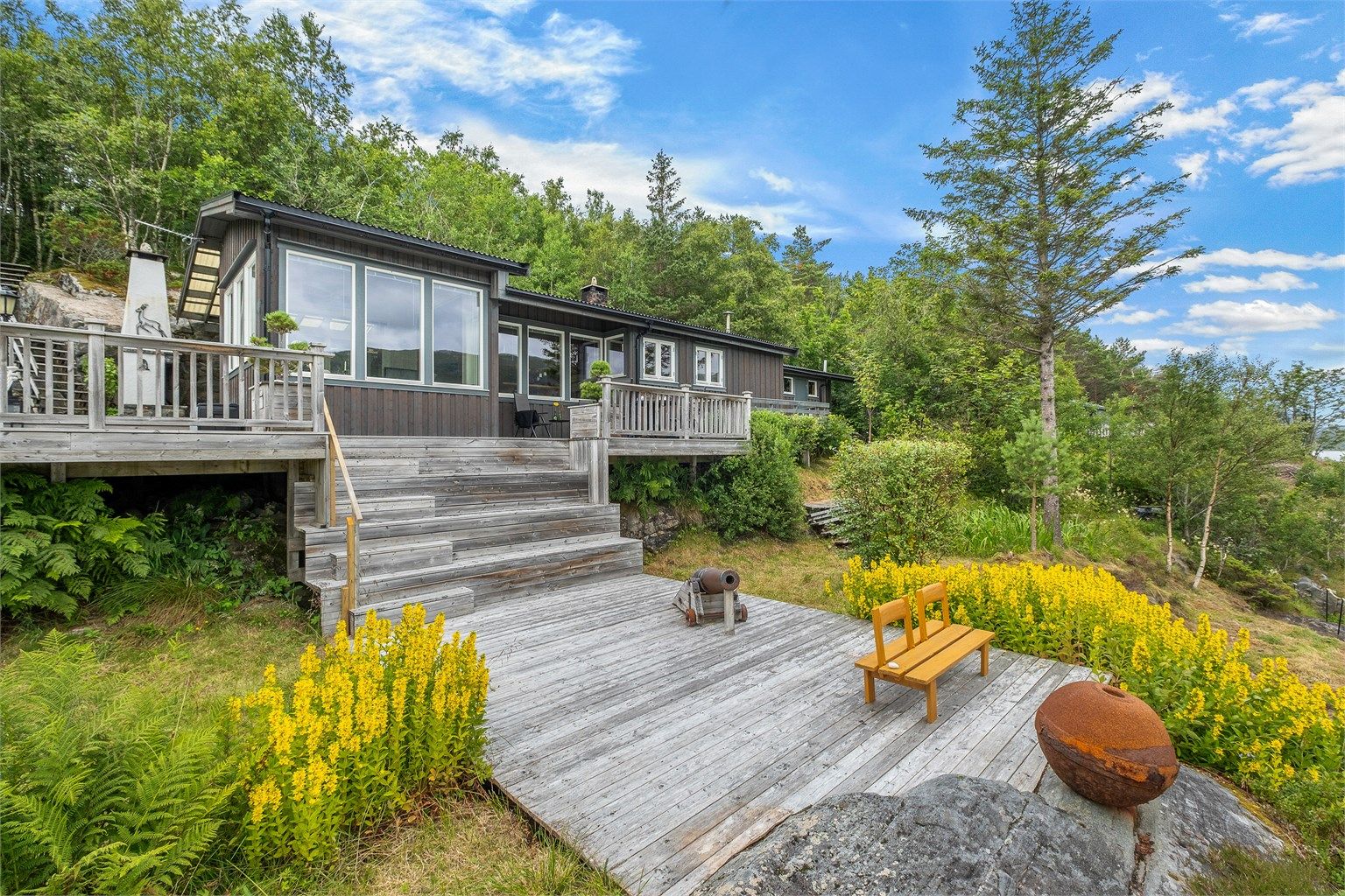 Fra sjøen leder trapper opp mot hytta og de romslige terrassearealene – fint integrert i den naturlige tomten.