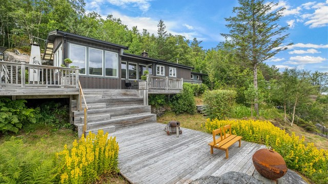 Fra sjøen leder trapper opp mot hytta og de romslige terrassearealene – fint integrert i den naturlige tomten.