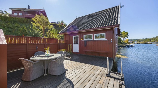 Eget båthus med loft og terrasseplatting ved sjøen.